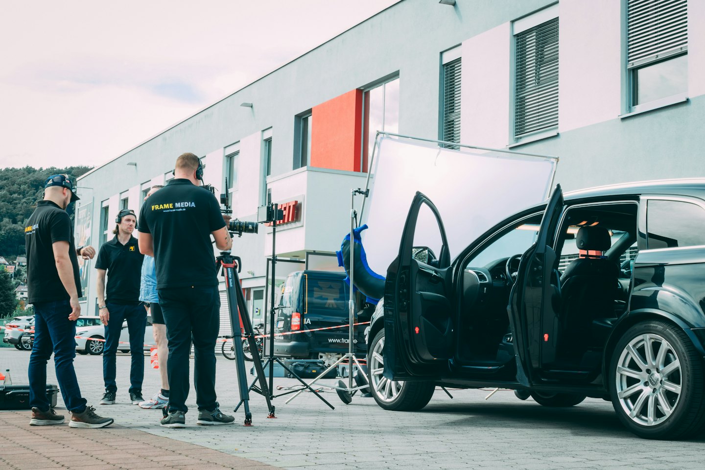 Film crew setting up video production outside a modern building.